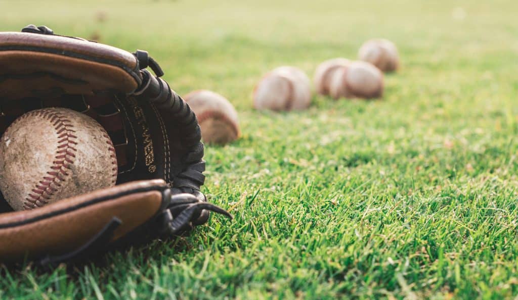 A baseball glove with a ball resting inside on a grassy field, symbolizing the best baseball players of the 70s and their enduring legacy.