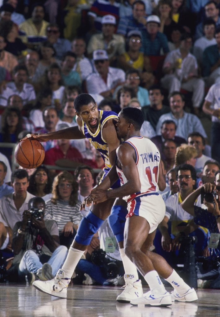 Magic Johnson of the Los Angeles Lakers backing down Isiah Thomas of the Detroit Pistons during an intense matchup, showcasing two of the best NBA players of the 80s in action.