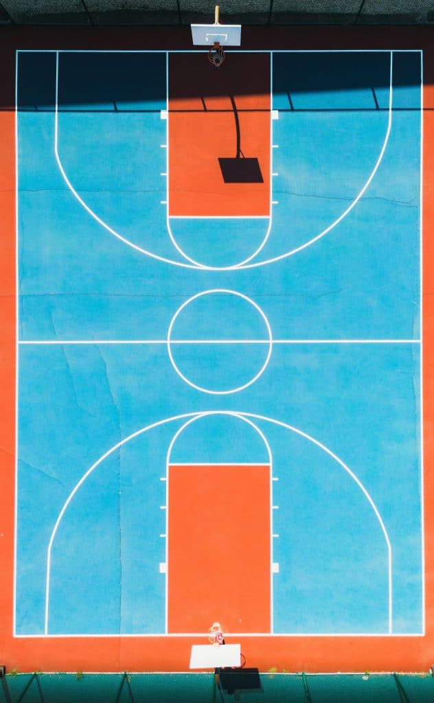 Aerial view of a vintage-style basketball court with vibrant red and blue colors, symbolizing where Best NBA Players In The 70s used to play.