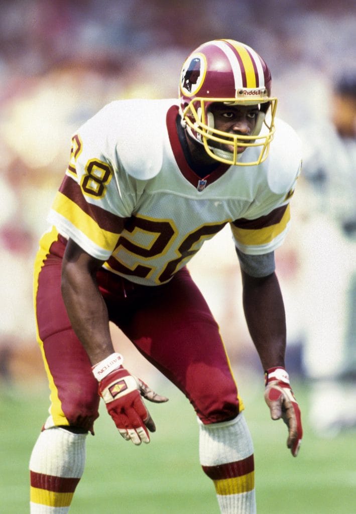Darrell Green in Washington Redskins uniform, crouched in defensive stance, ready to cover a receiver