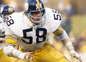 Pittsburgh Steelers linebacker Jack Lambert (#58) crouching in an action stance during a game, wearing the team's classic black and yellow uniform.