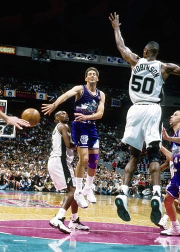 Jeff Hornacek of the Utah Jazz jumps to make a pass while David Robinson of the Spurs attempts to block during a playoff game.