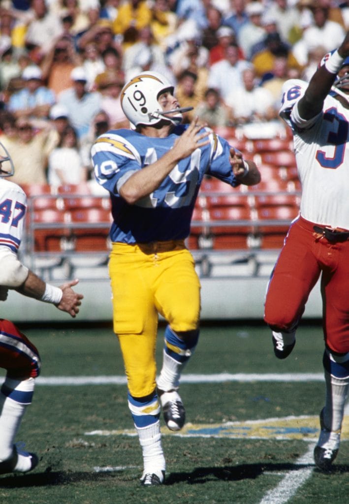 Lance Alworth of the San Diego Chargers leaps for a pass during a game with defenders nearby.