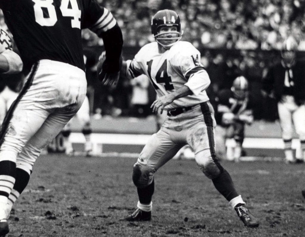 Y.A. Tittle, quarterback for the New York Giants, prepares to throw a pass during a game, pursued by defenders.