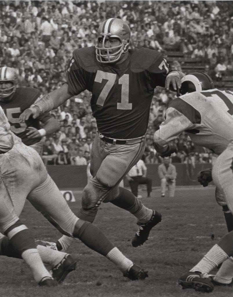 Alex Karras, Detroit Lions defensive tackle, wearing number 71, rushing the quarterback during a game.
