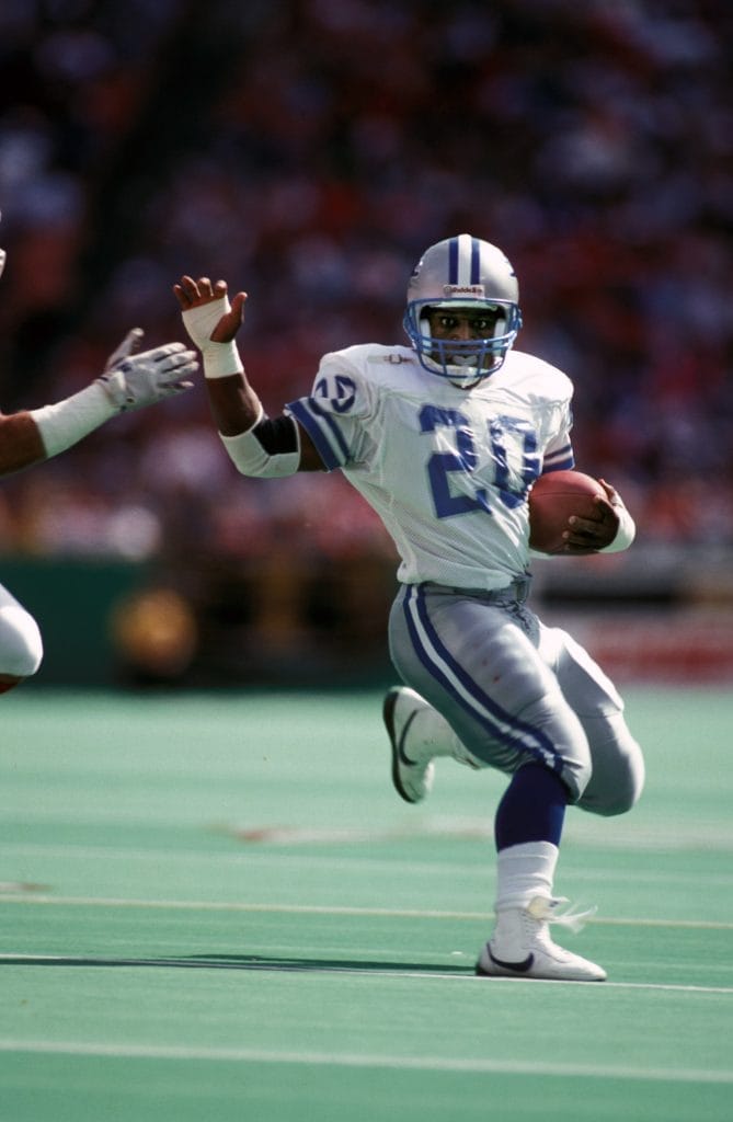 Barry Sanders evading defenders during a Detroit Lions game, showcasing his signature agility.