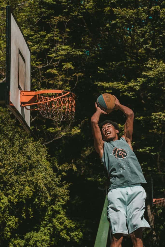 A basketball player performing an impressive dunk on an outdoor court, representing the best dunkers of all time who brought excitement to the game.