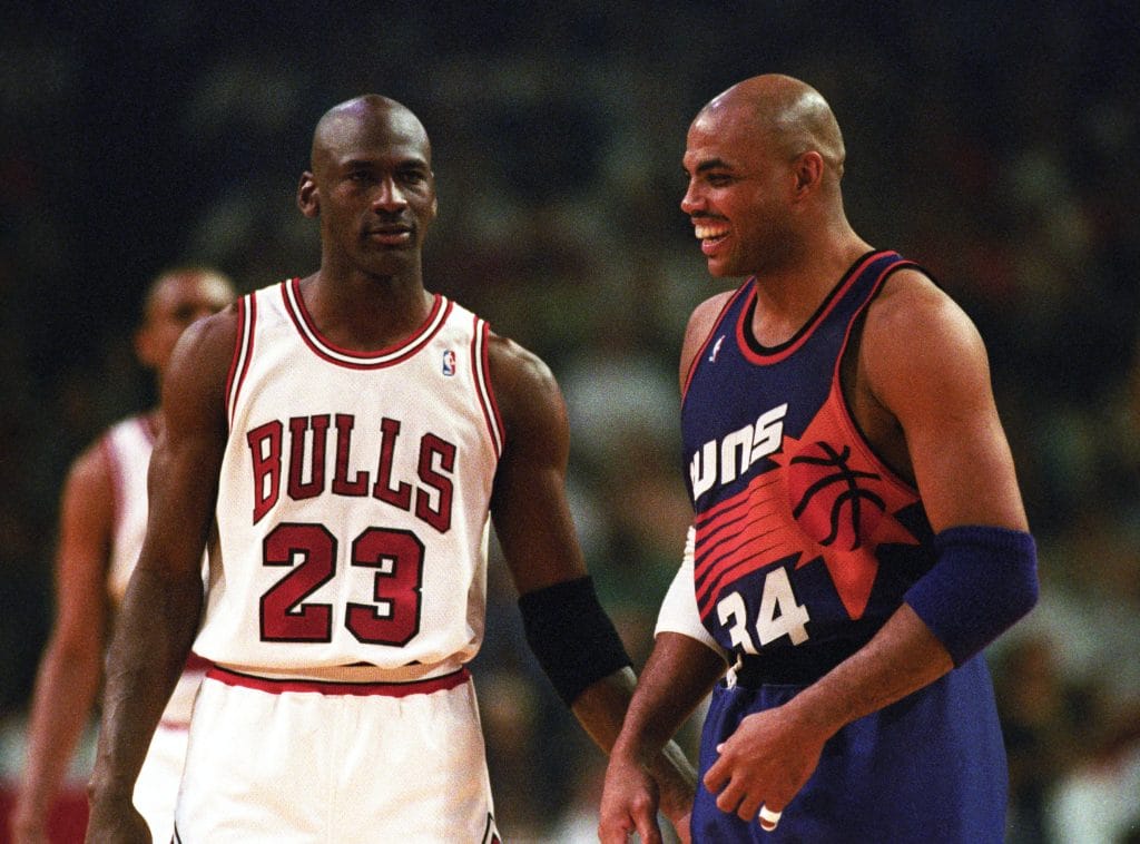 Michael Jordan of the Chicago Bulls and Charles Barkley of the Phoenix Suns sharing a moment during a game, exemplifying the best NBA players of the 90s.