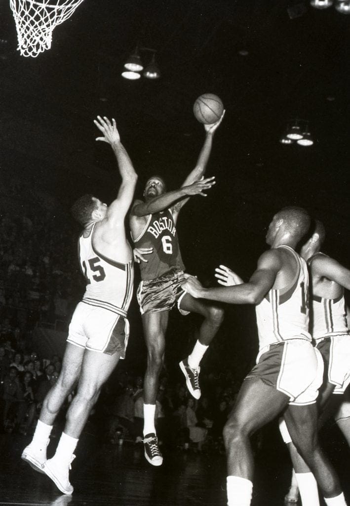 Bill Russell, legendary center for the Boston Celtics, executes a post move against defenders during an NBA game.