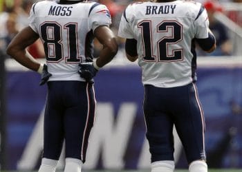 Tom Brady and Randy Moss of the New England Patriots discussing strategy on the field during a game representing 2 of Top 10 New England Patriots of All Time.