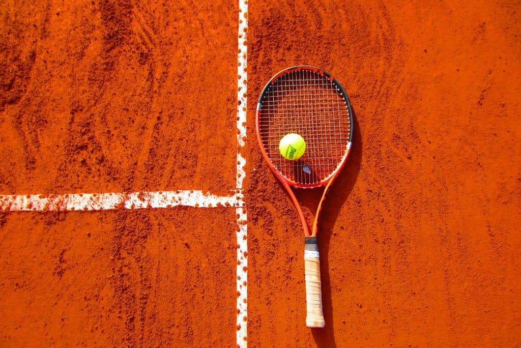 Tennis racket and ball on a clay court, symbolizing the skill and legacy of the greatest tennis players of all time.