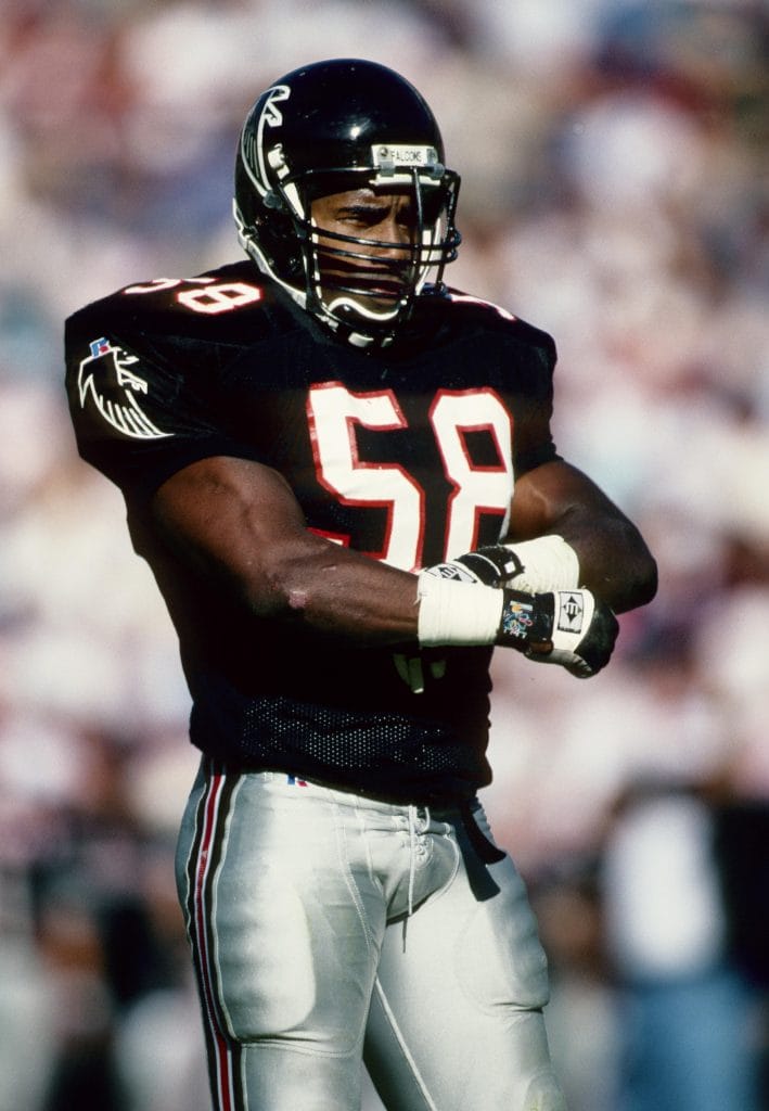 Jessie Tuggle in a black Atlanta Falcons uniform during a game, standing with arms crossed.