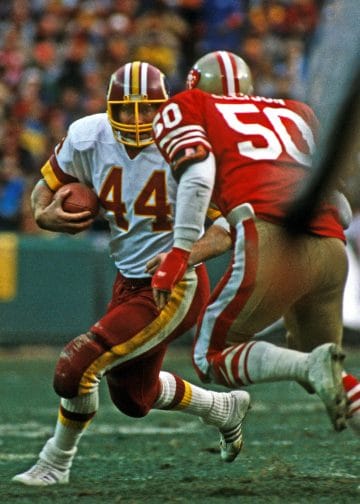 John Riggins of the Washington Redskins runs with the ball during a game against the San Francisco 49ers.