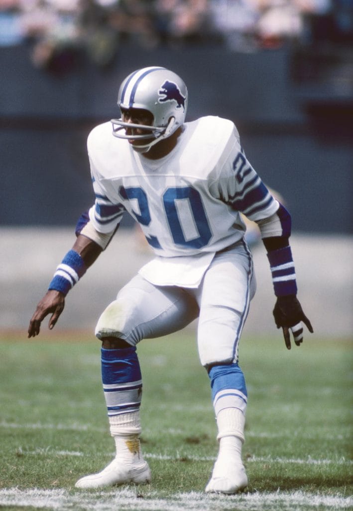 Lem Barney in a Detroit Lions uniform, crouching in a defensive stance during a game.