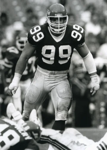 Mark Gastineau in action during a New York Jets game, wearing his #99 jersey, displaying his aggressive play style on the field.