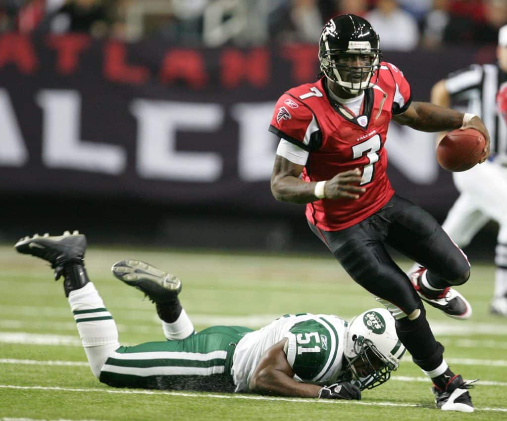 Michael Vick running with the football in a game for the Atlanta Falcons, evading a New York Jets defender.