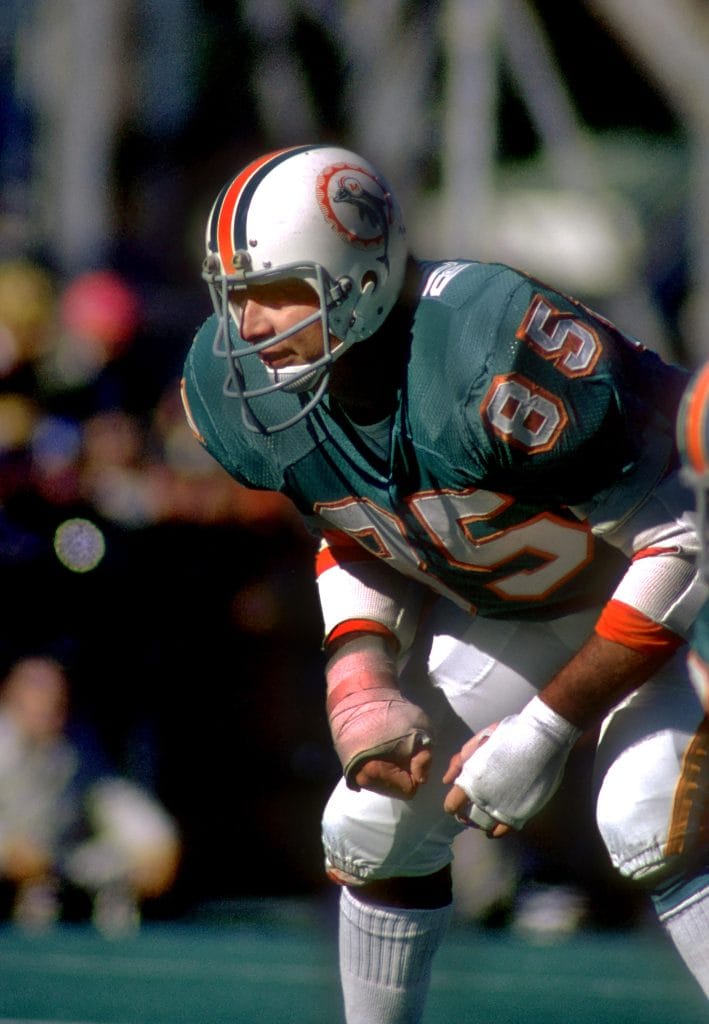 Nick Buoniconti in a Dolphins uniform, crouched in a ready position with his hands wrapped during a game.