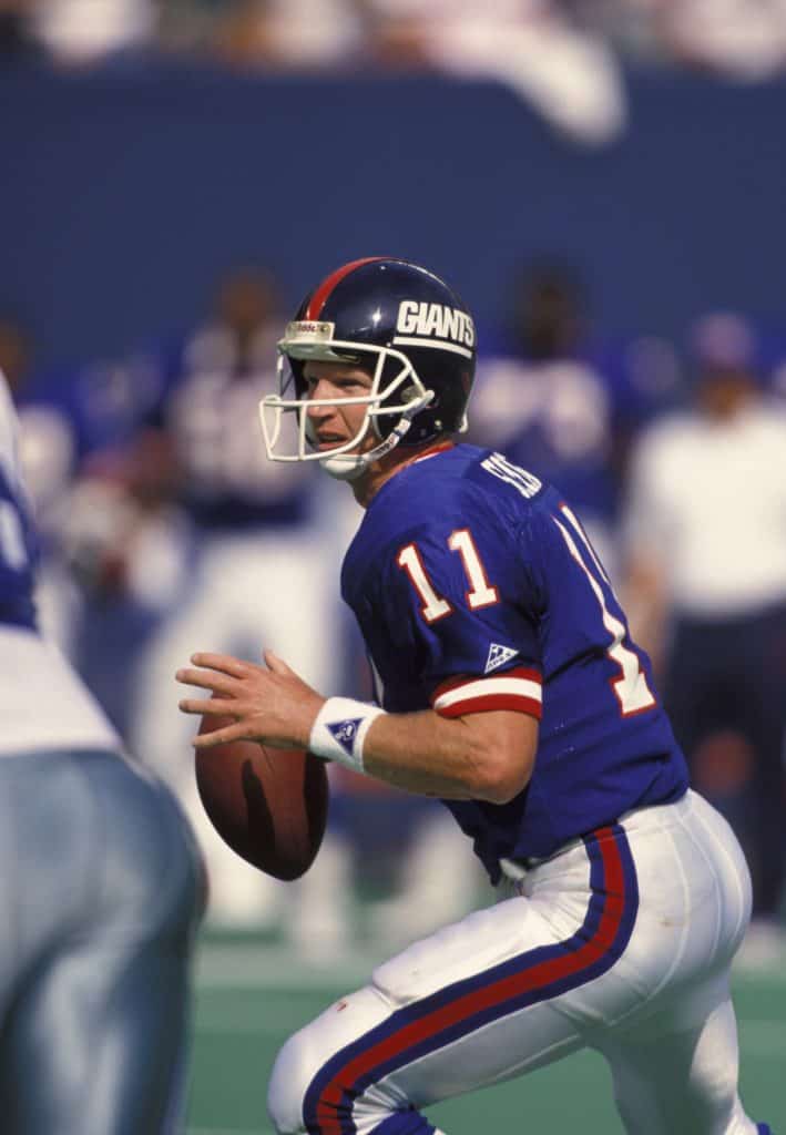 New York Giants quarterback Phil Simms looking downfield during a game, preparing to throw a pass.