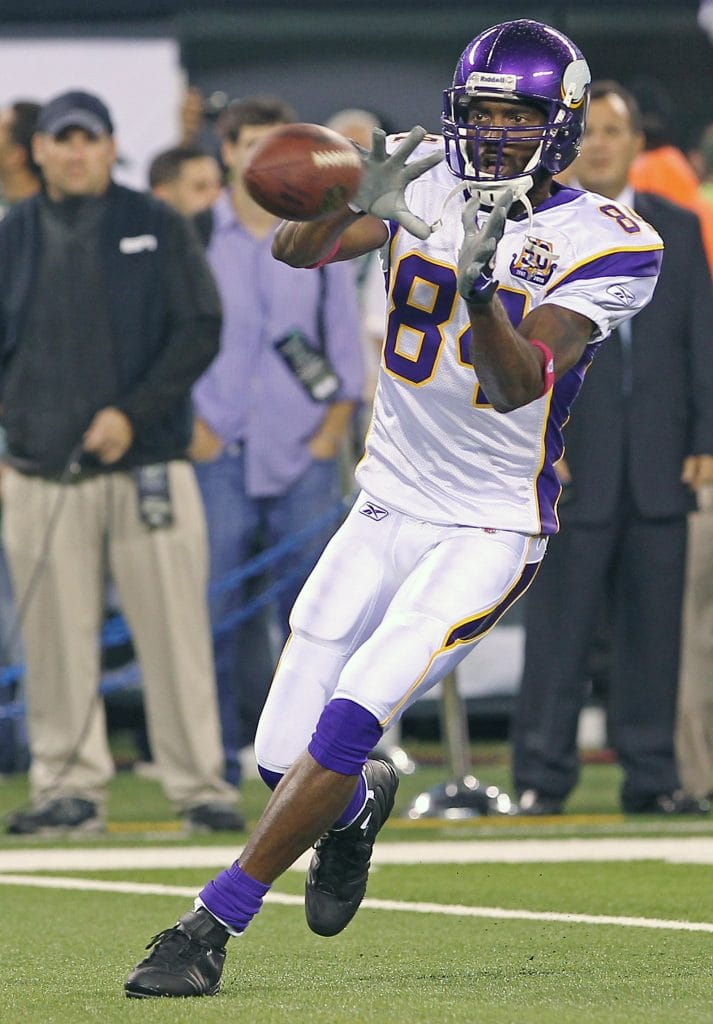 Randy Moss of the Minnesota Vikings reaching out to catch a football during a game.