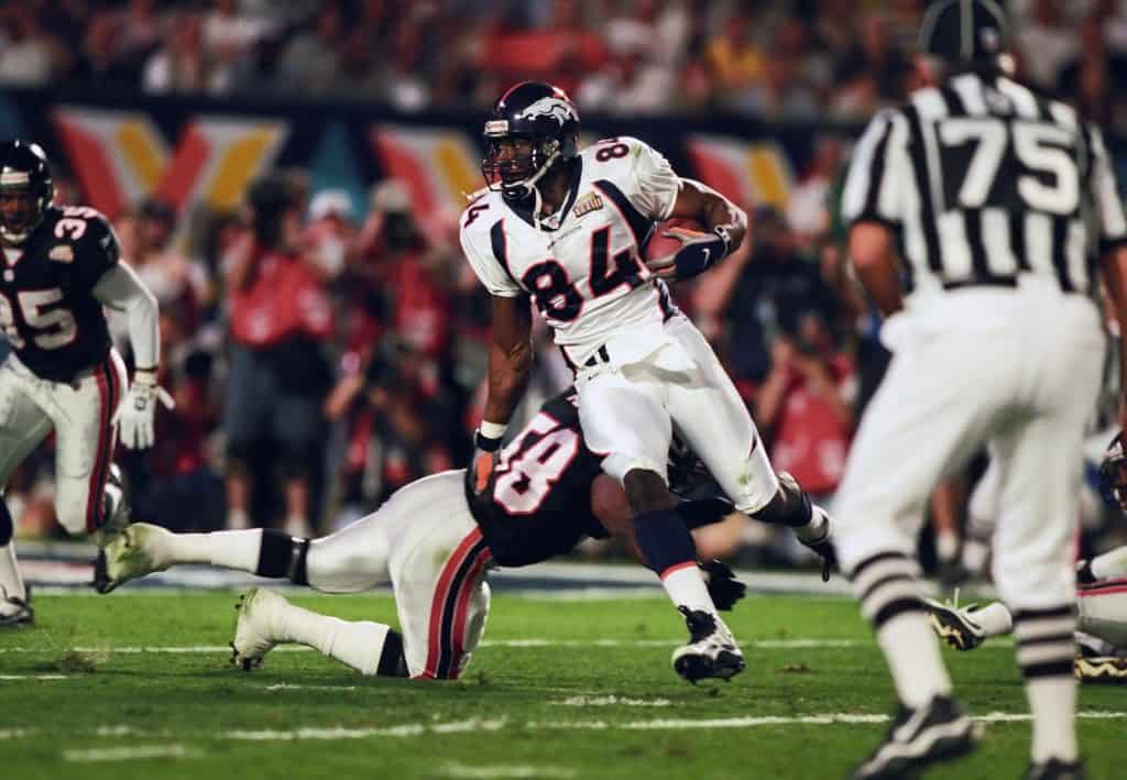 Denver Broncos tight end Shannon Sharpe breaking a tackle during a game, showing his athleticism and strength.