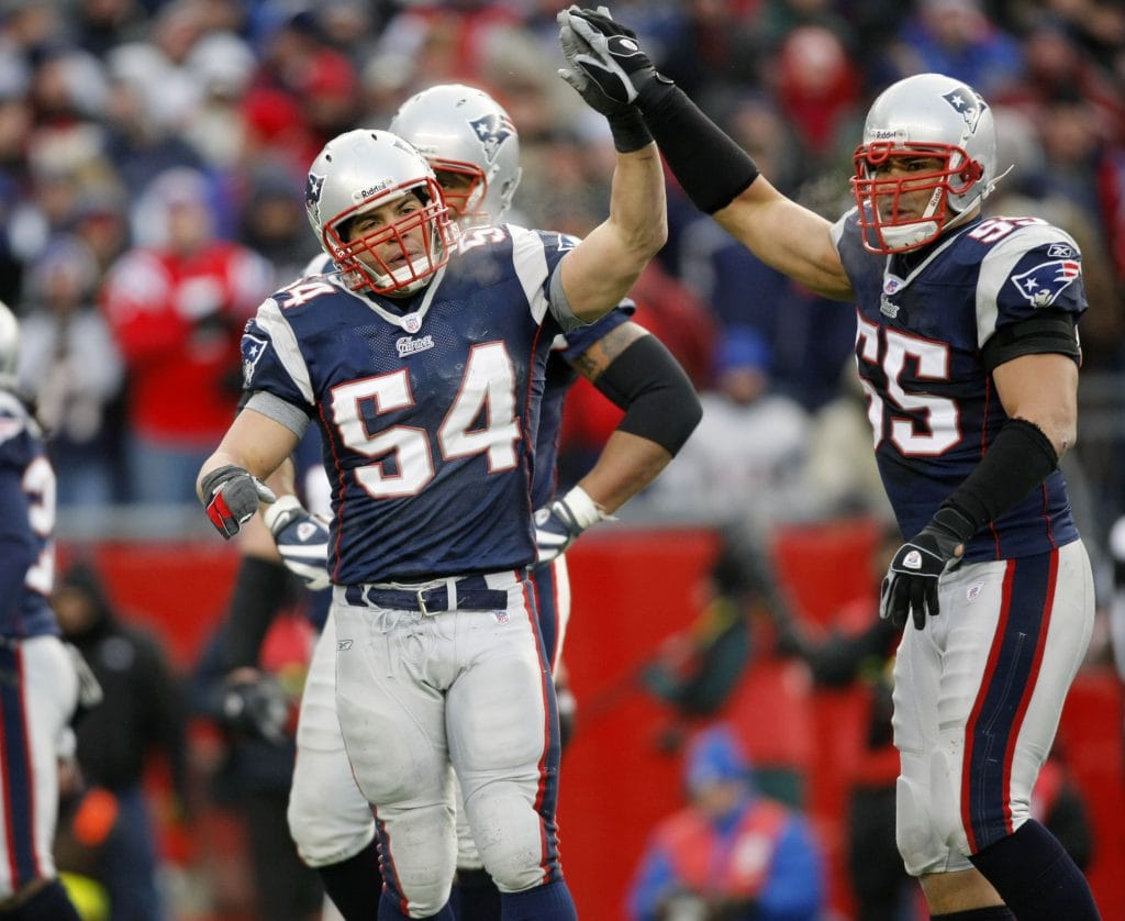 Tedy Bruschi of the New England Patriots, wearing number 54, giving a high-five to teammate Mike Vrabel during a game.