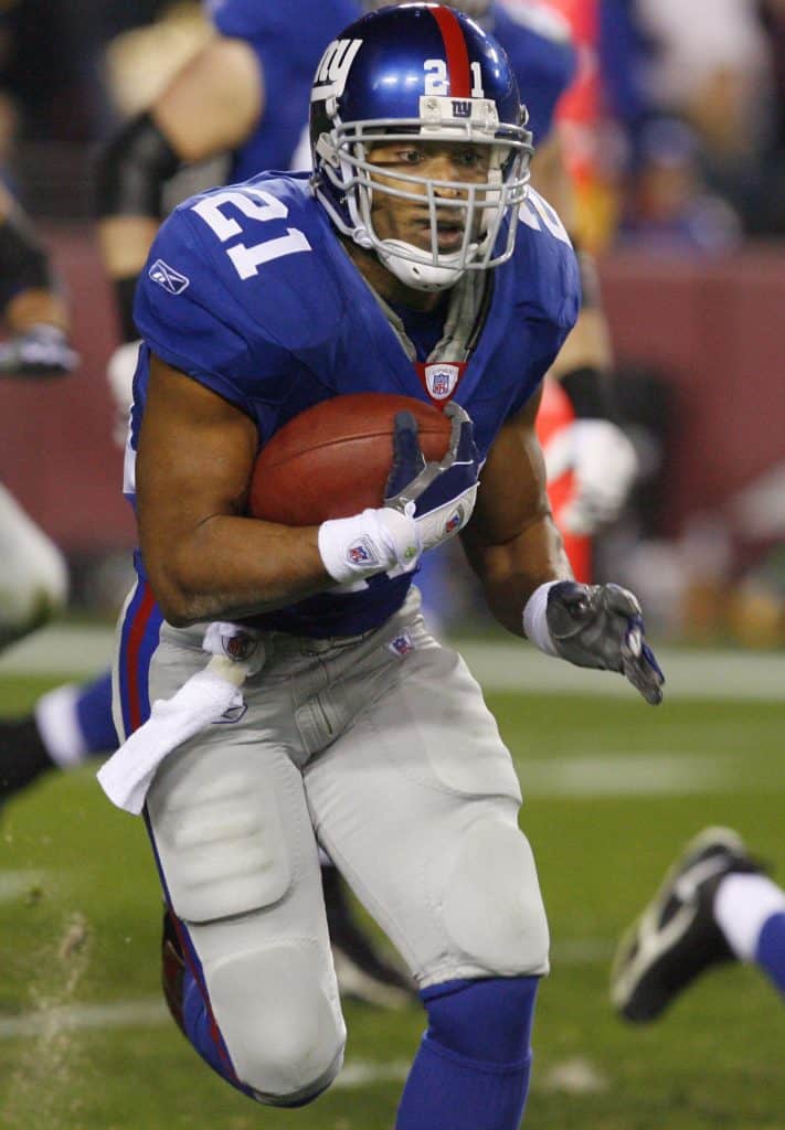 Tiki Barber running with the football for the New York Giants during a game.