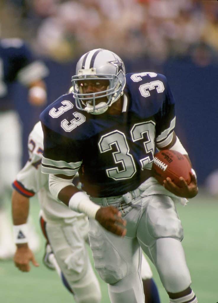 Tony Dorsett of the Dallas Cowboys carrying the ball during a game, evading defenders.