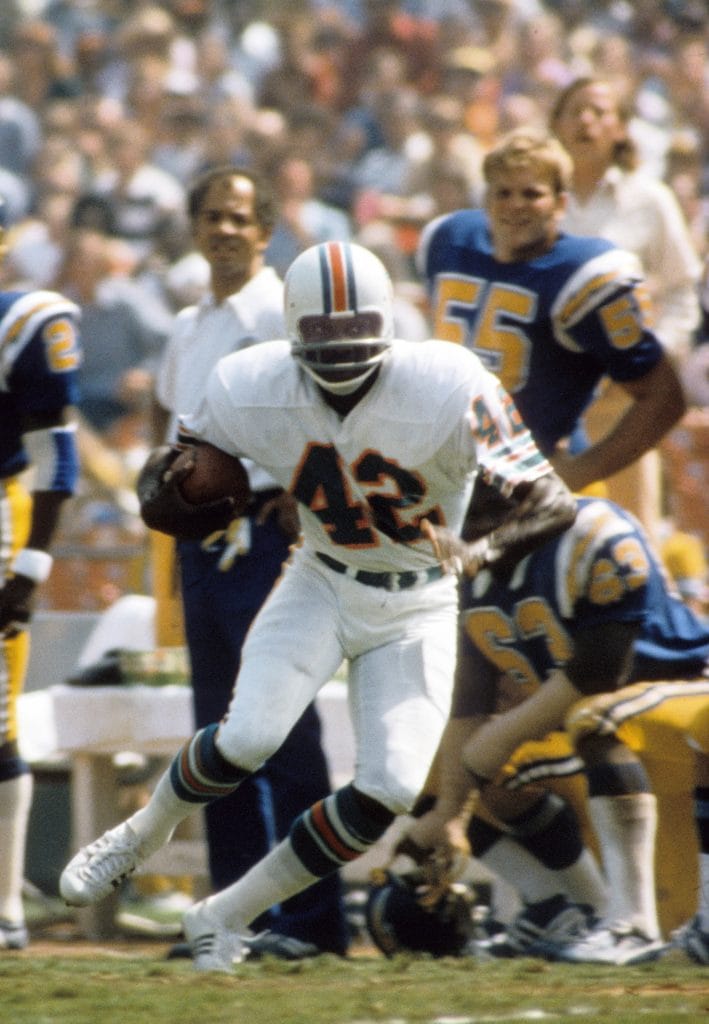 Miami Dolphins player Paul Warfield (#42) running with the football during a game, with San Diego Chargers defenders visible in the background.