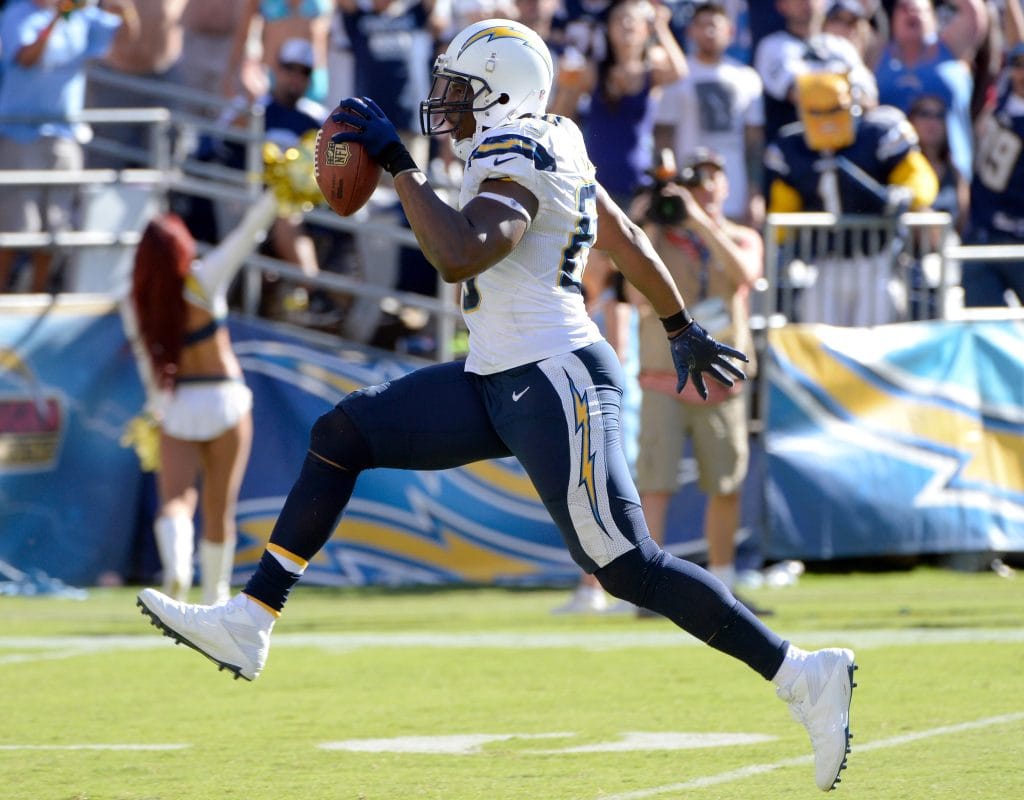 Antonio Gates celebrating a touchdown for the Chargers, holding the ball high while running across the end zone.