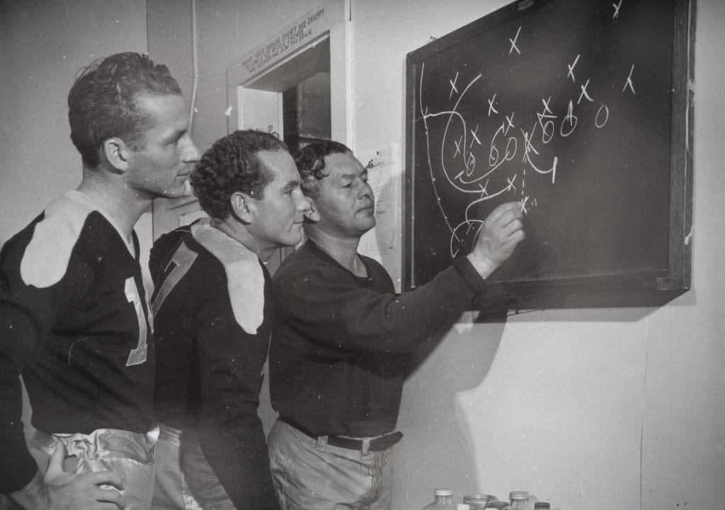 Don Hutson diagramming plays on a chalkboard, one of the best white nfl players of all time and a legendary white wide receiver in NFL history. 
