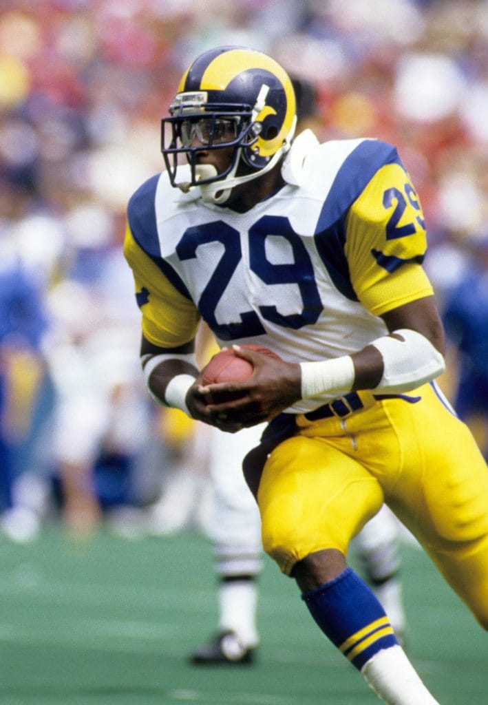 Eric Dickerson running with the football in a Rams uniform during an NFL game.