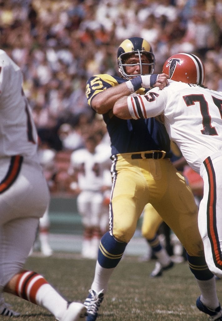 Conceptual image showcasing George Kunz in blocking action against Jackie Slater, highlighting two of the most famous white football players in NFL history.