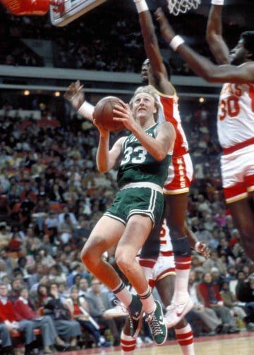 Larry Bird skillfully driving to the hoop against the Atlanta Hawks, showcasing his court vision and scoring ability.