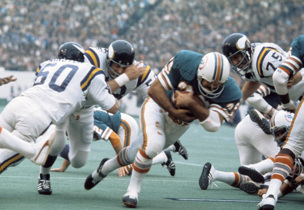 Larry Csonka of the Miami Dolphins dives forward while being tackled during a game against the Minnesota Vikings.