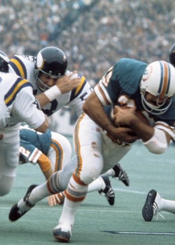 Larry Csonka of the Miami Dolphins dives forward while being tackled during a game against the Minnesota Vikings.