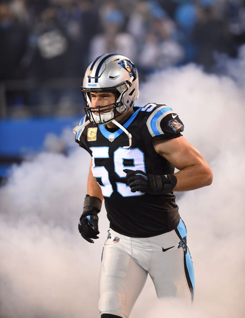 Carolina Panthers linebacker Luke Kuechly runs onto the field through smoke during player introductions.