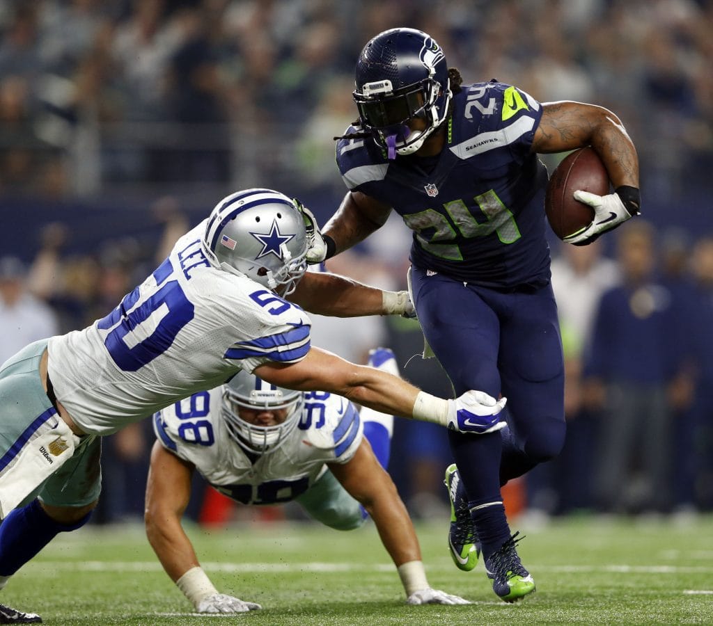 Marshawn Lynch of the Seattle Seahawks breaks a tackle attempt from Dallas Cowboys defenders during an NFL game.