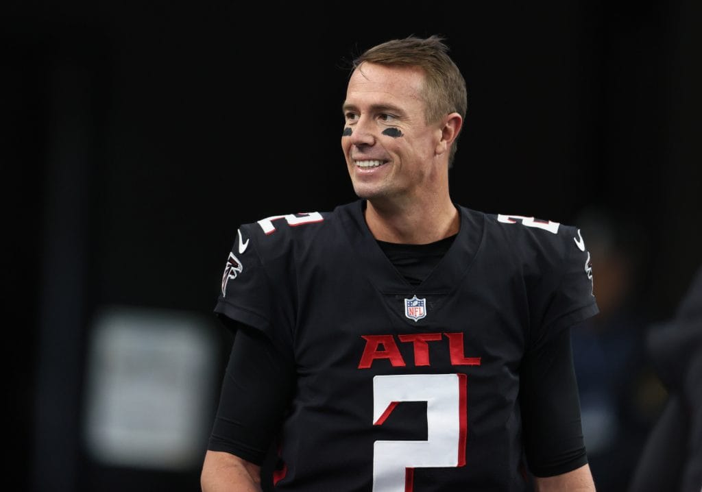 Matt Ryan smiles on the sideline while wearing the Atlanta Falcons' black uniform during a game.