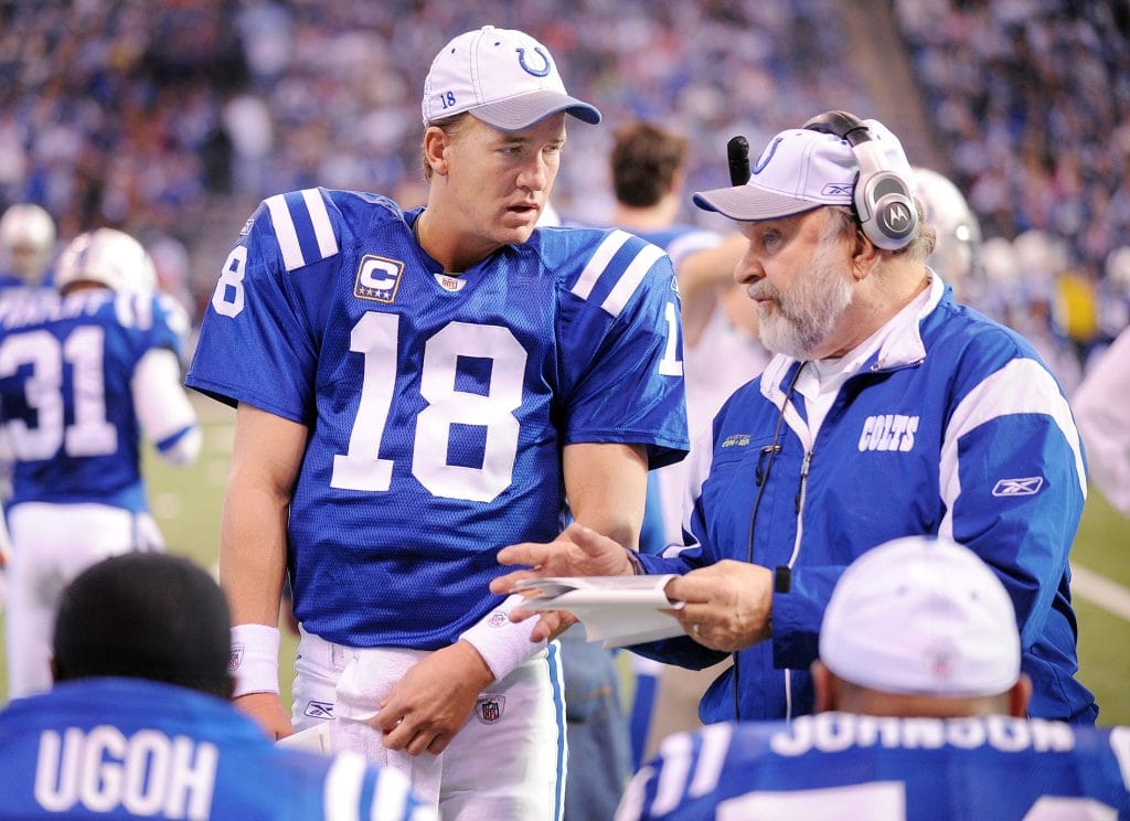 Peyton Manning discusses strategy with a Colts coach on the sideline during an NFL game.