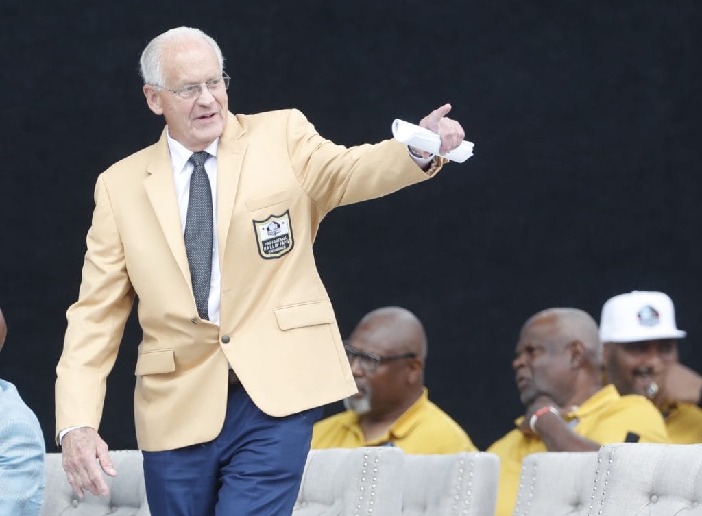 Randy Gradishar gestures during his Hall of Fame induction ceremony, wearing the iconic gold jacket.