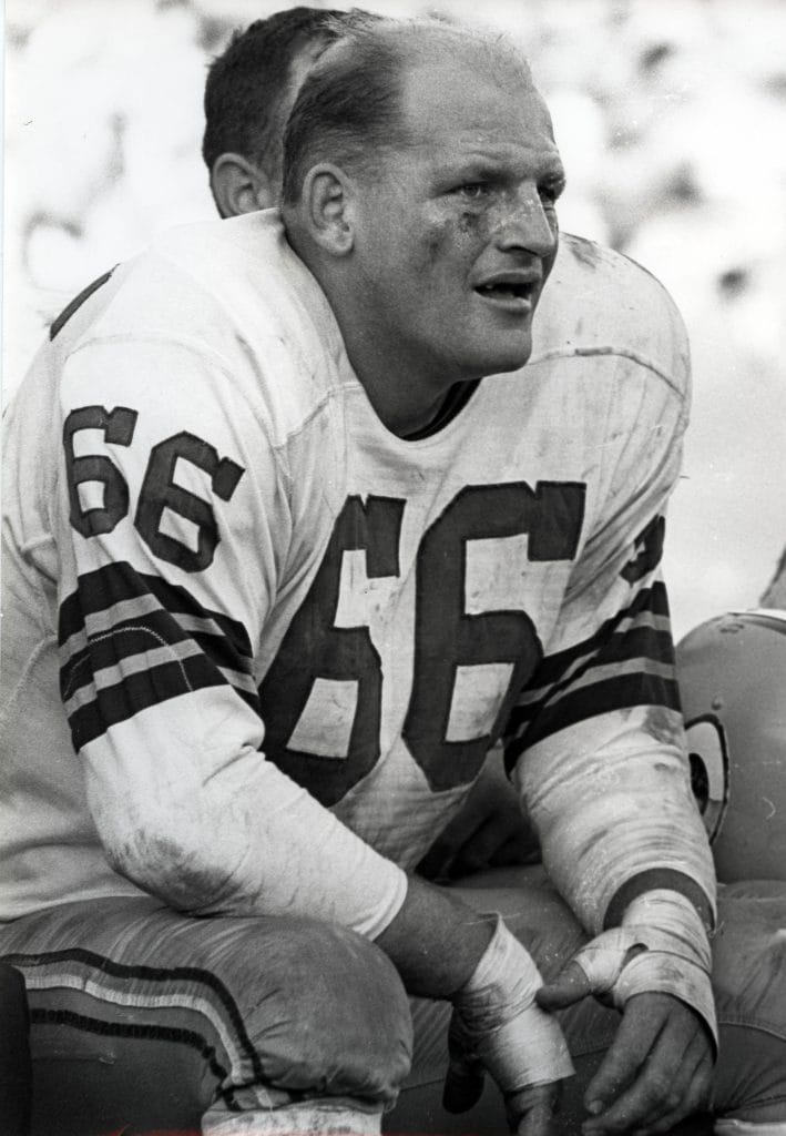 Ray Nitschke of the Green Bay Packers sits on the sideline during a game, wearing a dirty uniform with a "66" jersey.