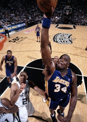 Shaquille O'Neal of the Los Angeles Lakers soaring for a powerful dunk against the San Antonio Spurs in a high-stakes playoff matchup.