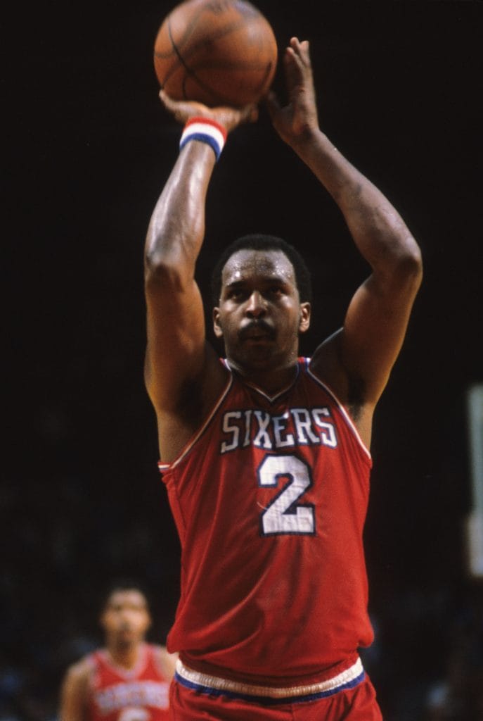 Philadelphia 76ers center Moses Malone taking a free throw during a game, displaying his concentration and skill.