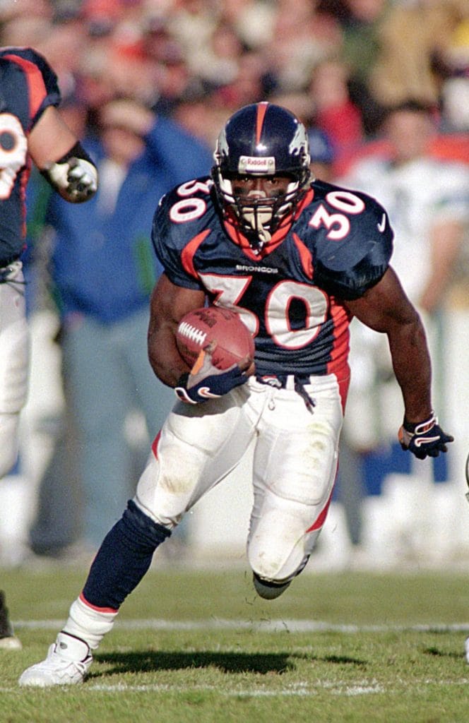 Terrell Davis carrying the football during a game, showcasing his powerful running style with the Denver Broncos.