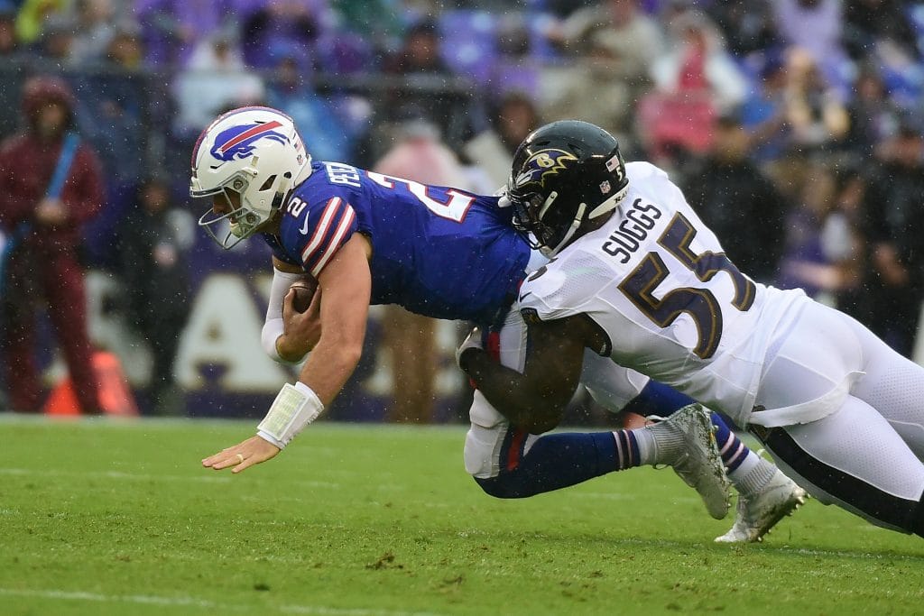 Terrell Suggs of the Ravens tackling a Bills quarterback during a rainy NFL game.