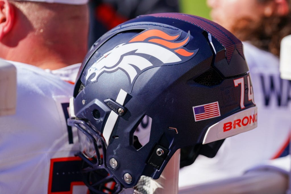 Close-up of a Denver Broncos helmet on the sideline, featuring the iconic logo and American flag decal, representing the Top 10 Denver Broncos of All Time.