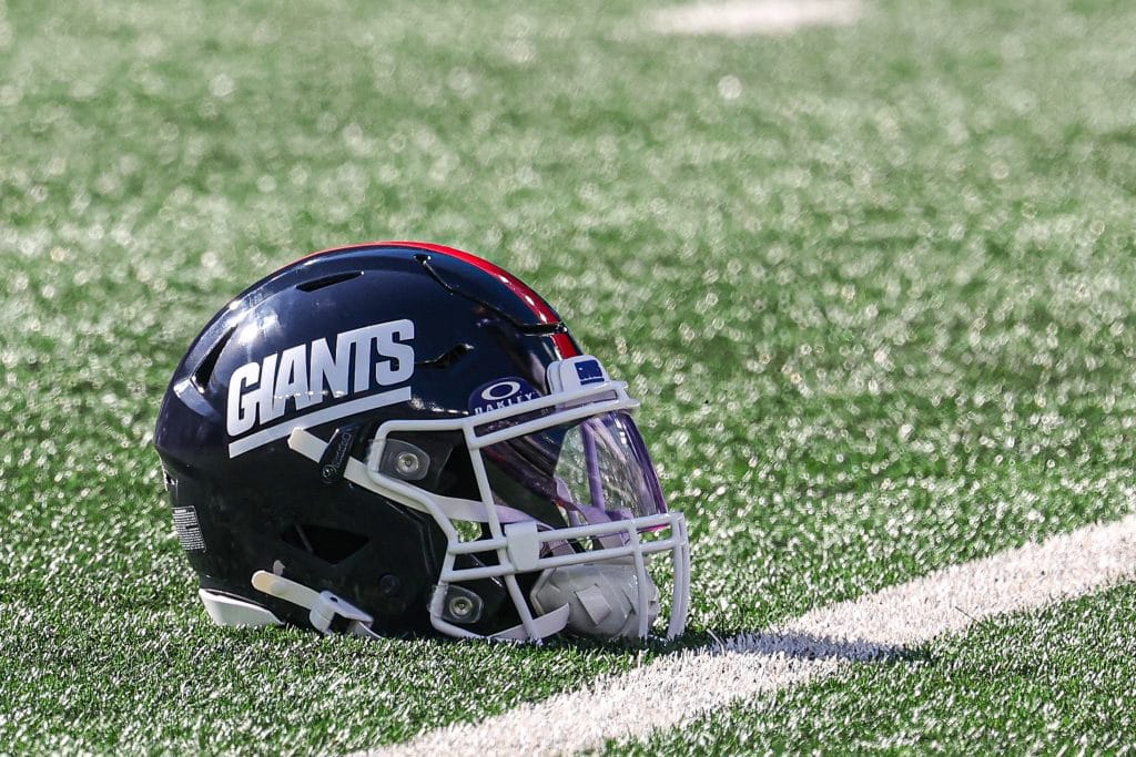 New York Giants helmet resting on the field, representing the storied history and players featured in the Top 10 New York Giants of All Time.