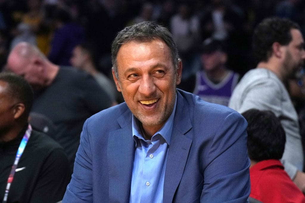 Vlade Divac smiling while on the sidelines at an NBA game.