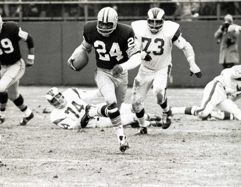 Willie Wood, wearing number 24, breaks through the Los Angeles Rams defense with the football