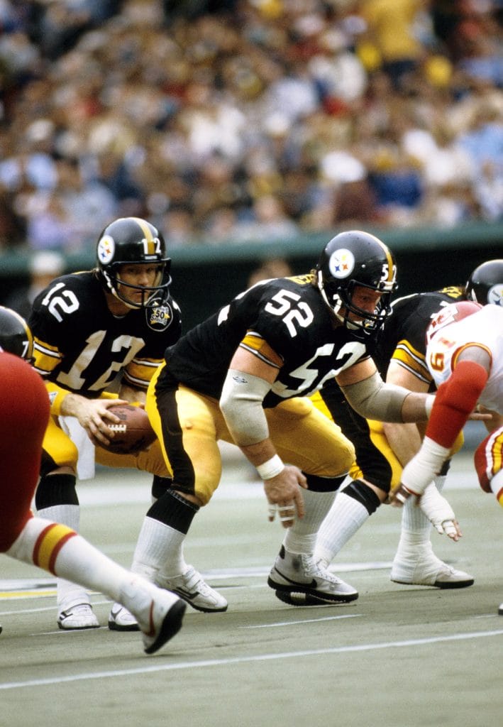 Mike Webster, regarded as one of the best white offensive linemen in NFL history, anchors the Pittsburgh Steelers' offensive line during a game.
